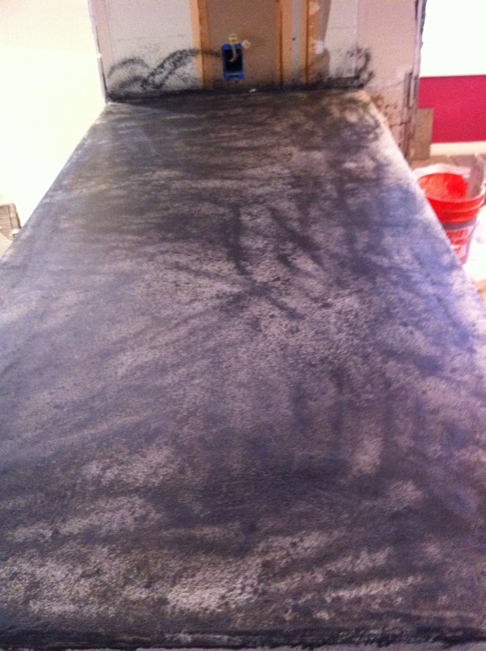 Countertop surface with dark speckled finish, unfinished wall behind it with electrical box