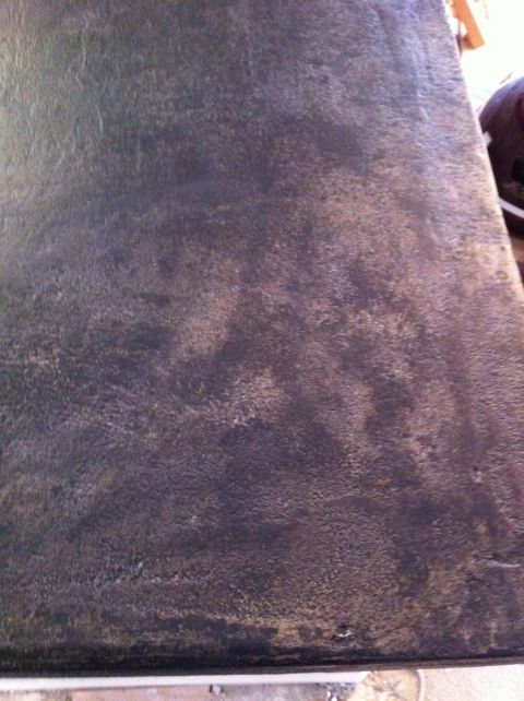 1989 Yugo Cabrio - The image shows a close-up of a worn, dark-colored surface with a textured appearance.