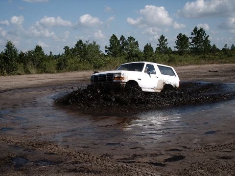 1996 Ford Bronco - White 1996 Ford Bronco navigates a muddy obstacle course during an off-road event.