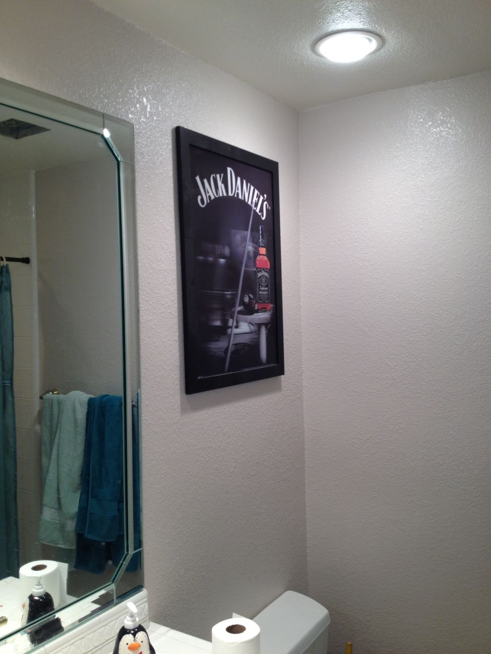 Bathroom with Jack Daniel's poster, mirror, towels, and toilet paper