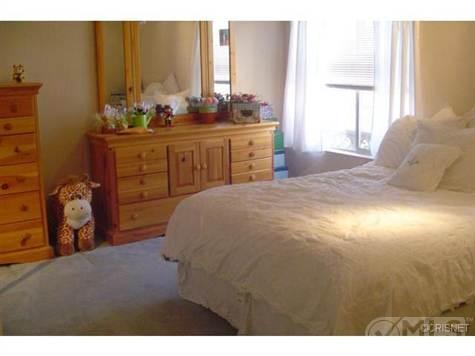 1989 Yugo Cabrio - Bedroom scene a dresser, a stuffed toy, and a bed with white linens.