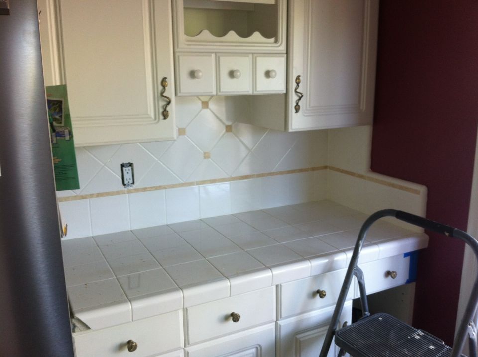Kitchen counter with white tiled backsplash and cabinets. A step ladder is partially visible on the right