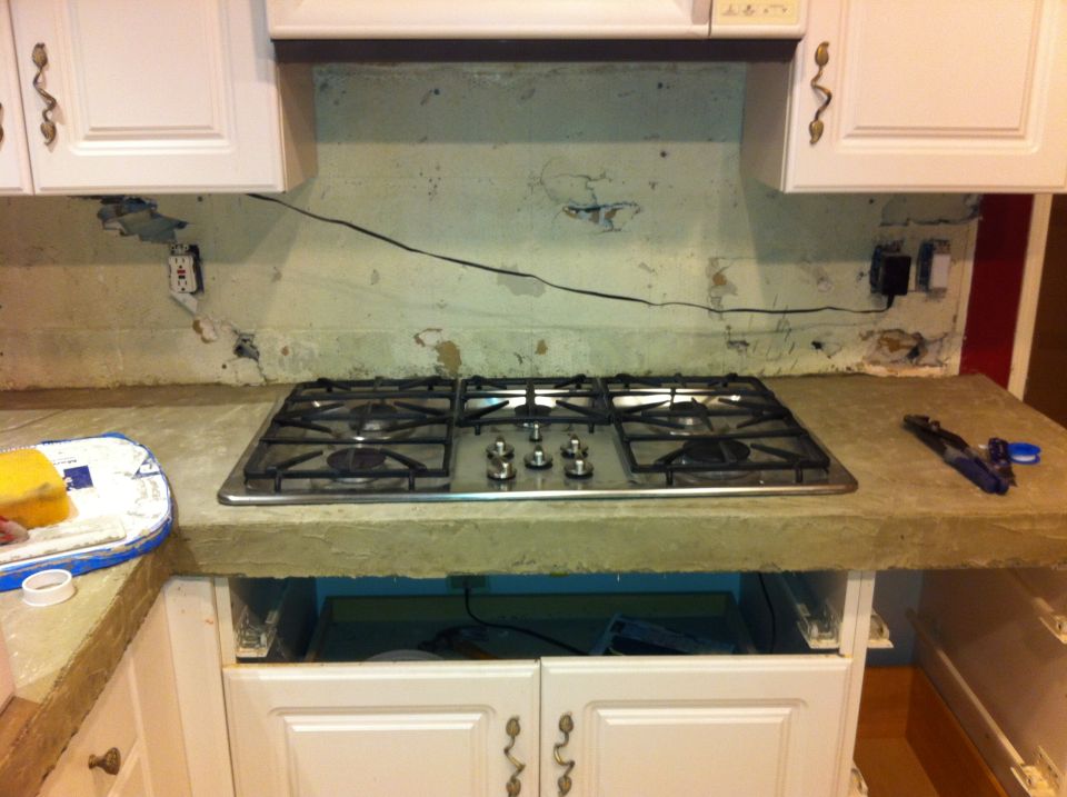 Kitchen countertop with a stainless steel gas stove, white cabinets, and exposed wiring