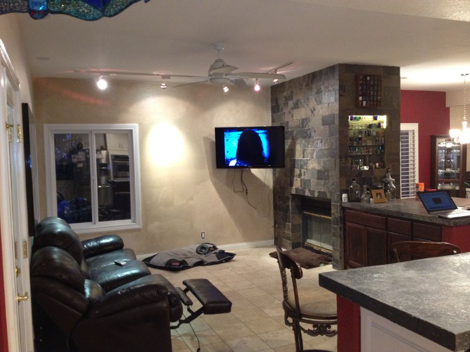 Living room with leather sofa, fireplace, bar, and television