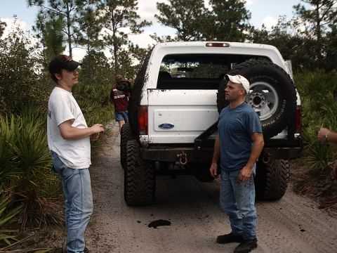 1996 Ford Bronco - A white 1996 Ford Bronco is seen from the rear, covered in mud, with two men standing nearby.
