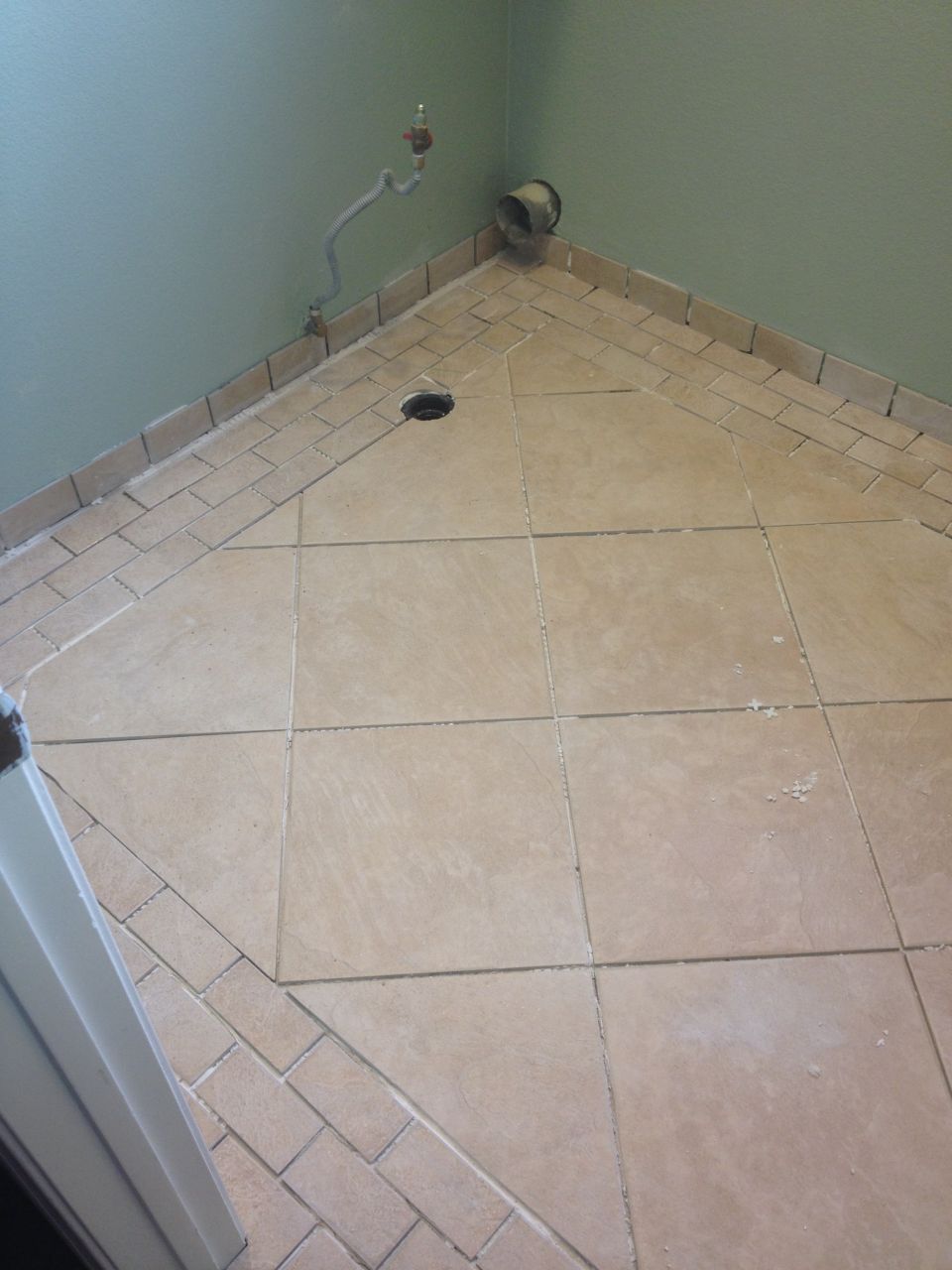tiled corner with drain, pipe, and vent