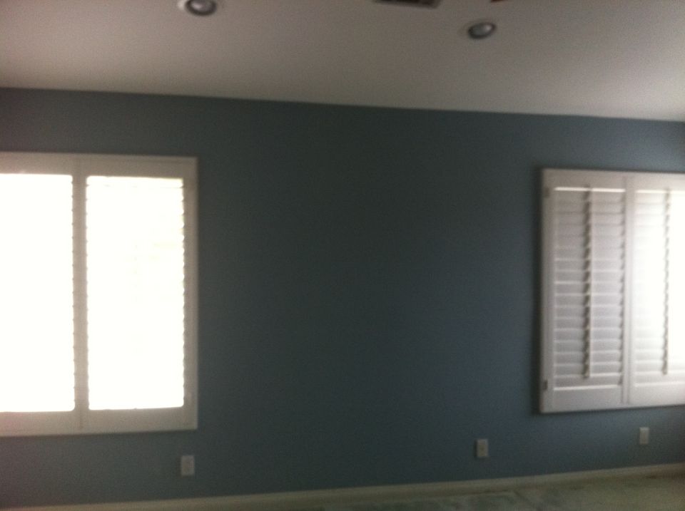 Interior room with dark blue walls, two windows with white shutters, and a watermark for Supermotors.net