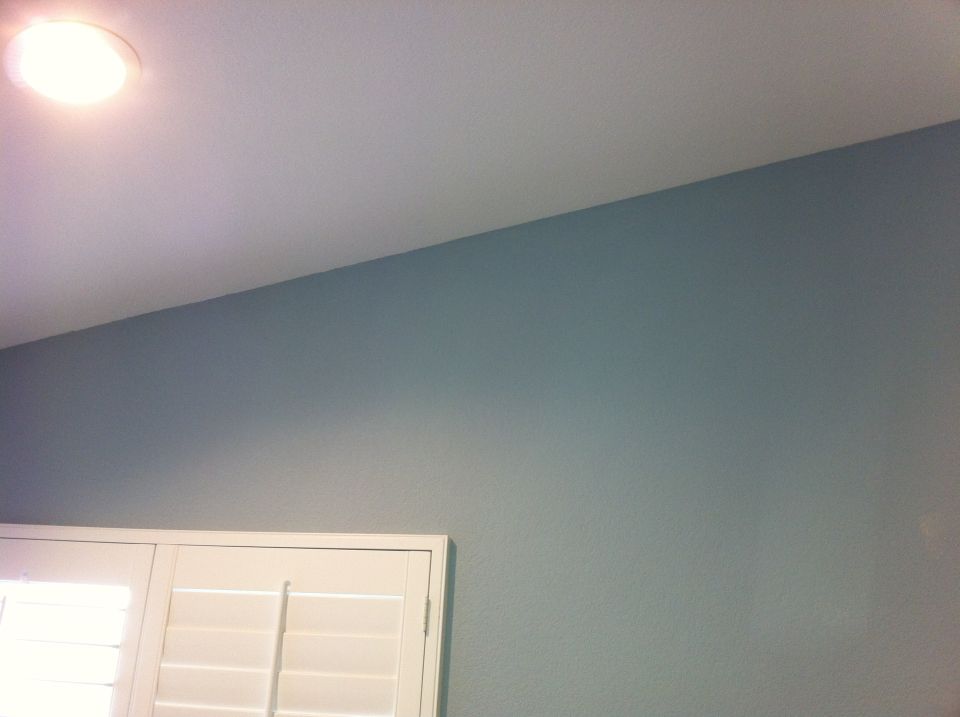 Interior shot showing a ceiling light, a light blue wall, and white shutters