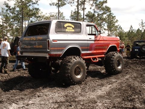 1996 Ford Bronco - This modified SUV, possibly a 1978 Ford Bronco, navigates a muddy course with other vehicles in the background.
