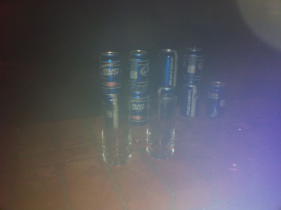 Bud Light cans stacked on drinking glasses on a wooden surface