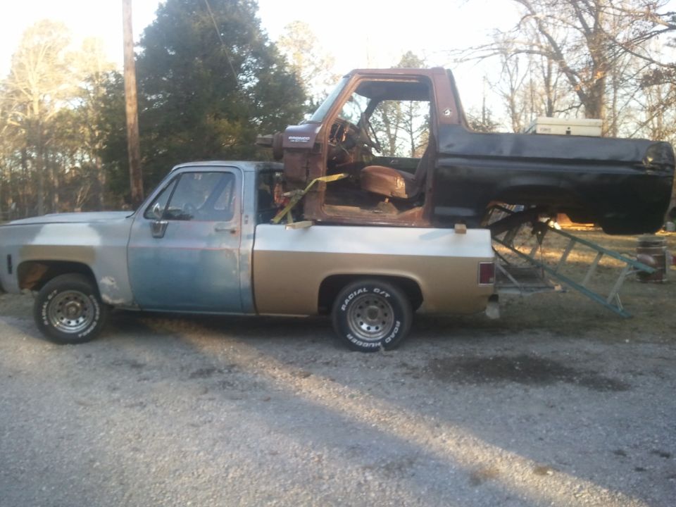 Side view of a pickup truck with a disassembled Bronco body loaded in the bed