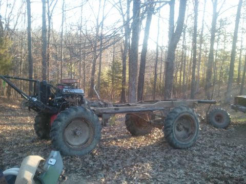 1978 Ford Bronco - This custom vehicle chassis sits in a wooded area with large tires and exposed engine components.