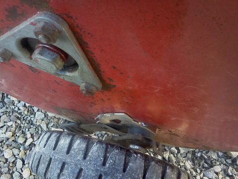 1991 Toyota Tacoma - Close-up view of a red panel with bolted hardware and a tire, likely part of a vehicle's undercarriage.