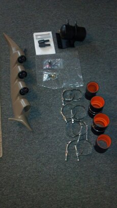 1993 Ford F-150 - A tan gauge pod with three gauges, a black turbo boost gauge, and various hose clamps and adapters are laid out on a carpeted surface.