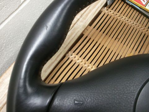 1989 Ford Bronco - A close-up shot focuses on a leather-wrapped steering wheel, with a magazine visible in the background.