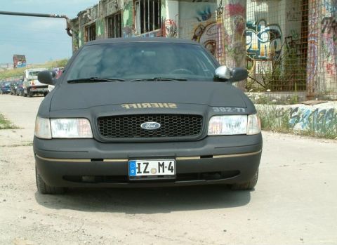 2003 Ford Crown Victoria - Matte black 2003 Ford Crown Victoria, likely a police interceptor, is shown from the front with "SHERIFF" text on the hood.