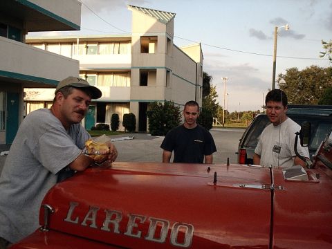 1996 Ford Bronco - Three men stand behind the hood of a red vehicle with "LAREDO" written on it.