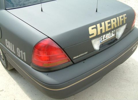 2003 Ford Crown Victoria - Rear view of a dark gray 2003 Ford Crown Victoria Police Interceptor with sheriff markings and a license plate.