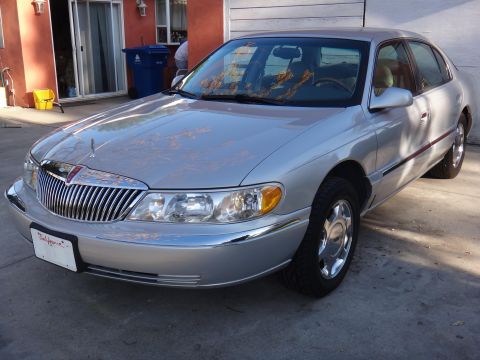 2000 Lincoln Continental - A silver sedan is parked in a driveway with a house and garage in the background.