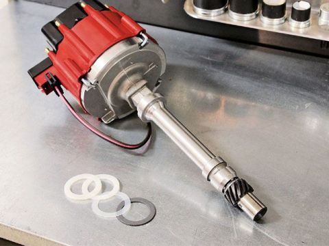1990 Ford Bronco - A red and silver distributor cap with associated wires and gaskets is shown on a metallic workbench.