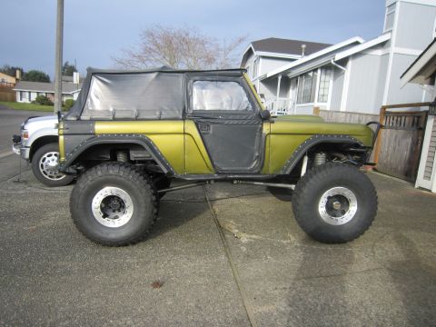 1974 Ford Bronco - Modified 1974 Ford Bronco with custom paint and off-road tires is parked on a driveway.