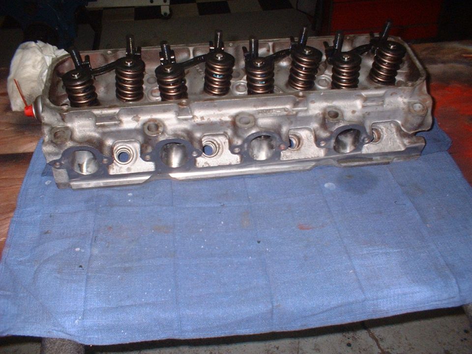 Engine cylinder head with rocker arms and springs, resting on a blue cloth