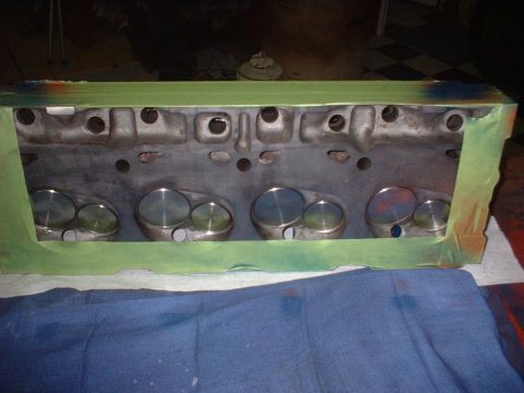 1969 Ford Torino - A close-up view of an engine cylinder head, with its valves visible and the top edges masked with green tape.