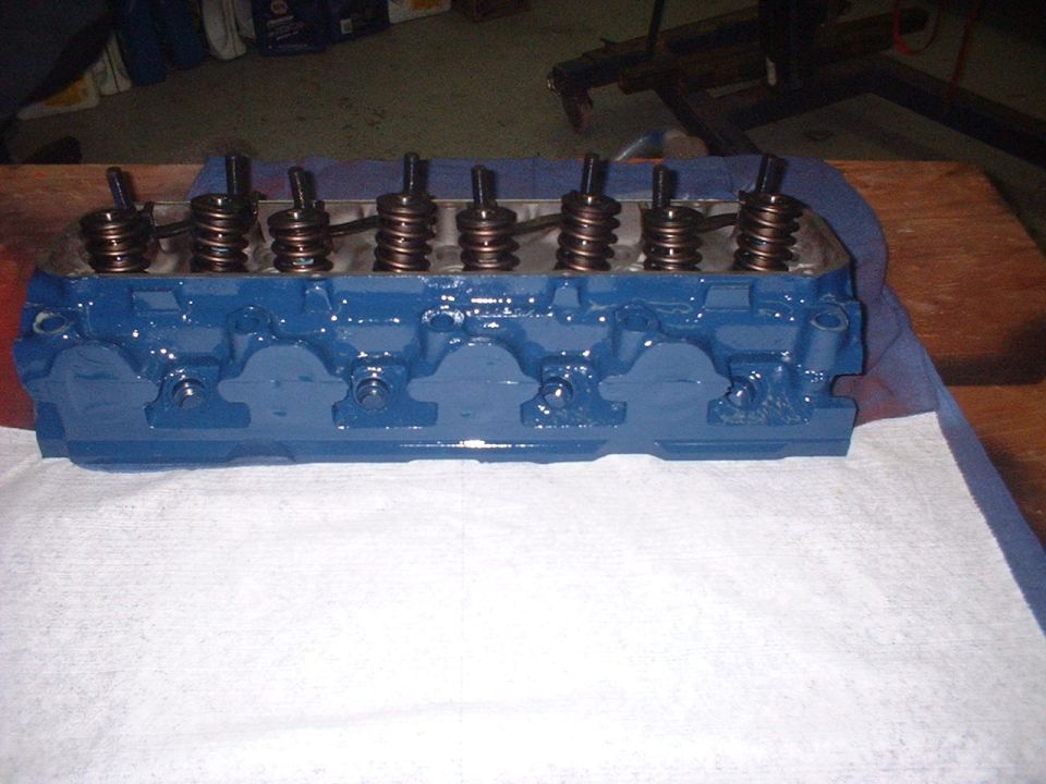 Blue painted engine cylinder head with visible valve springs and pushrods