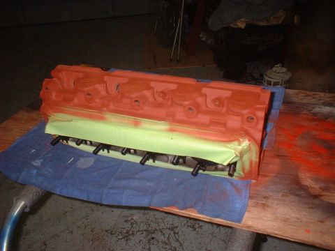 1969 Ford Torino - An engine component, possibly a cylinder head or intake manifold, is being painted orange and red.