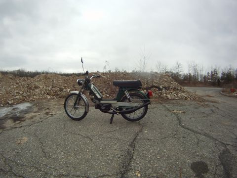 1981 Garelli Rally Sport - A green moped is parked on a cracked asphalt surface with piles of rubble behind it.