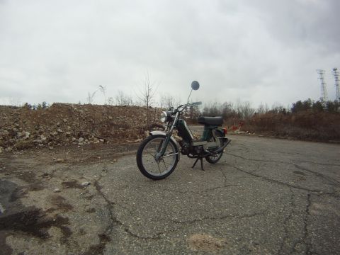 1981 Garelli Rally Sport - A green moped sits on a desolate road under an overcast sky.