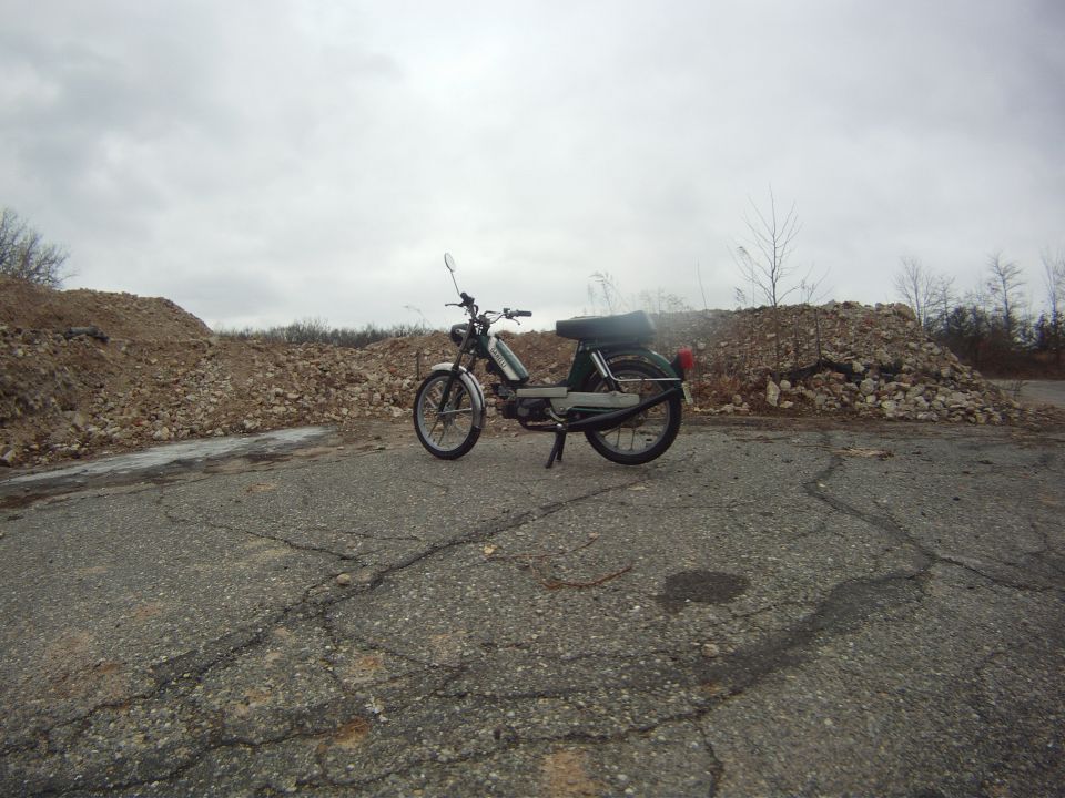 Moped parked on cracked asphalt with piles of rubble in background