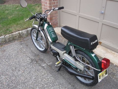 1981 Garelli Rally Sport - A green moped with chrome accents and a black seat is parked in front of a garage door.