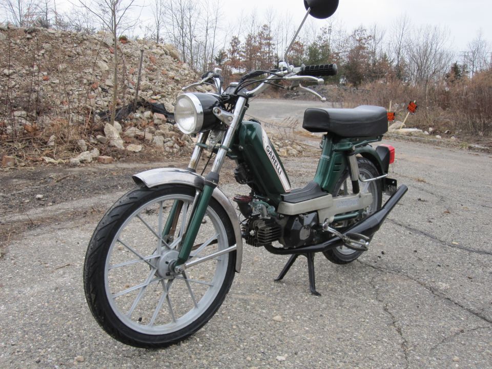 Green moped with chrome fenders and 'GARELLI' text on the side panel, parked on an asphalt road