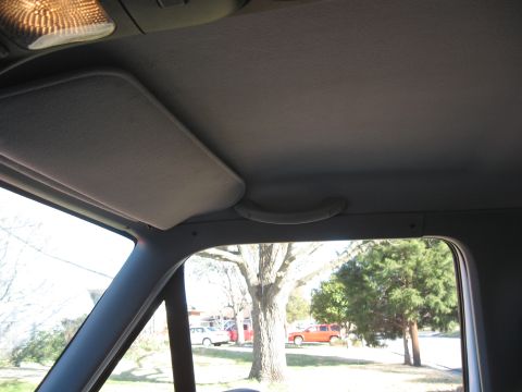 1994 Ford Bronco - View from inside a vehicle shows a sun visor and grab handle, with other vehicles and trees outside.
