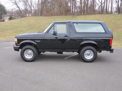 1996 Ford Bronco - Side profile of a black 1996 Ford Bronco SUV parked on asphalt.