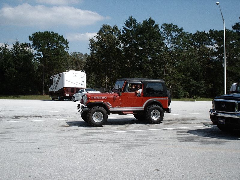 Red Jeep with black soft top and Laredo decals in a parking lot