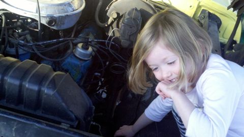 1978 Ford Bronco - A young child curiously peers into the engine compartment of a vehicle.