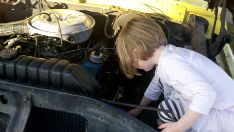 1978 Ford Bronco - A child explores the engine compartment of a vehicle.