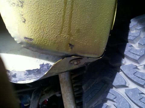 1978 Ford Bronco - Close-up view of a vehicle's body panel and tire, showing signs of wear and tear.
