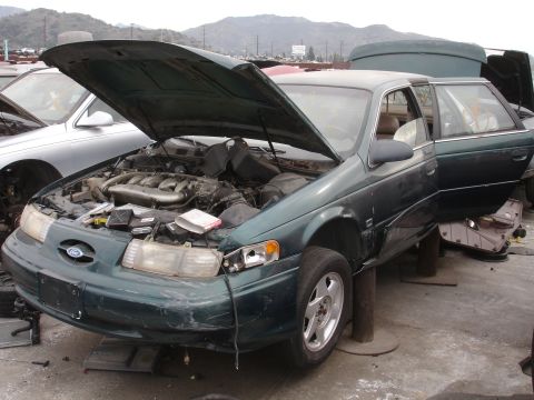 1993 Ford Taurus - Junkyard 1993 Ford Taurus with hood and driver door open, showing the engine bay.