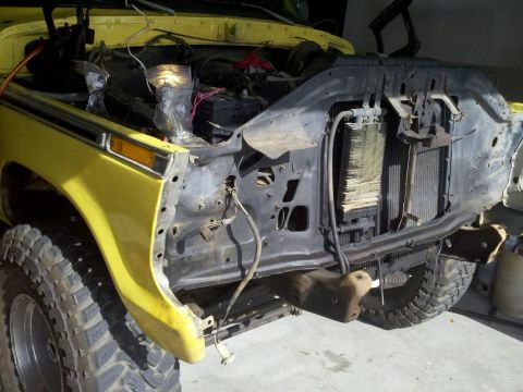1978 Ford Bronco - The front grille and radiator of a yellow truck are exposed, with the engine partially visible.