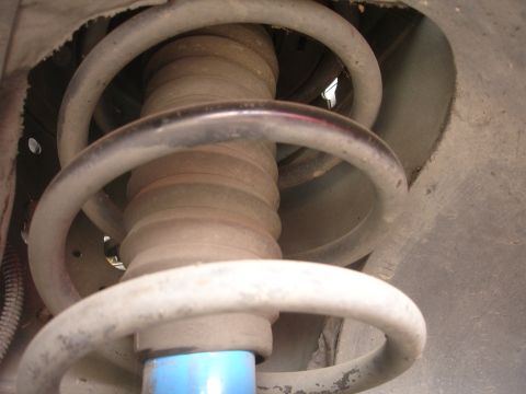 1993 Ford Taurus - Close-up view of a vehicle's front suspension system, showing the coil spring and a blue shock absorber.