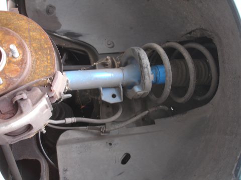 1993 Ford Taurus - Close-up view of a vehicle's front suspension system, showing a shock absorber and brake components.