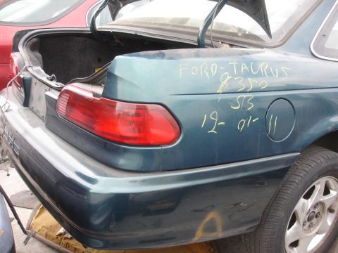 1993 Ford Taurus - The rear of a teal 1993 Ford Taurus sedan is shown with the trunk open and handwritten markings on the body panel.