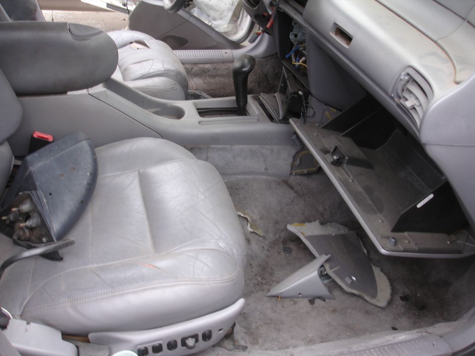 Interior of a 1993 Ford Taurus with gray leather seats, automatic transmission, and a damaged dashboard
