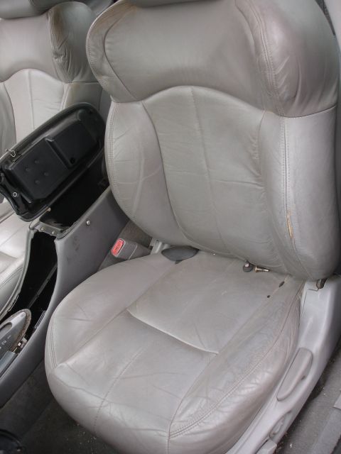 1993 Ford Taurus - The interior of a car features worn gray leather seats and a center console with an open storage compartment.
