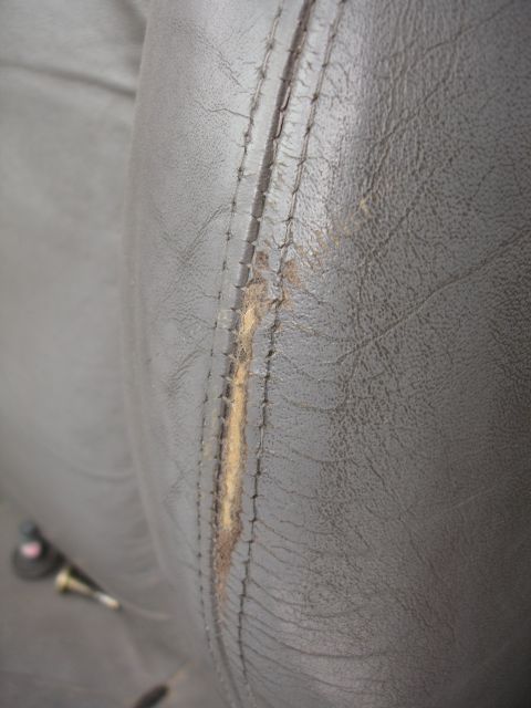 1993 Ford Taurus - Close-up of a damaged car seat interior, revealing worn leather and exposed stuffing.