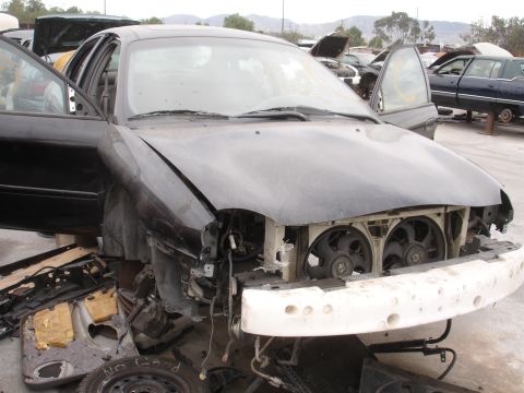 1993 Ford Taurus - Front view of a damaged 1993 Ford Taurus at a junkyard, with parts removed.