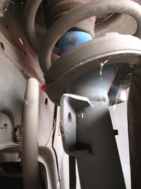 1993 Ford Taurus - A close-up view of a vehicle's suspension system, focusing on the strut and coil spring assembly.